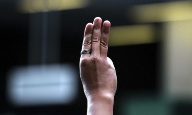 A protester flashes three fingers representing liberty, brotherhood and equality — similar to the revoluntaries’ salute in ‘The Hunger Games’ — during an anti-coup demonstration at a Bangkok, Thailand, shopping center Sunday. Photo: Wason Wanichakorn/AP