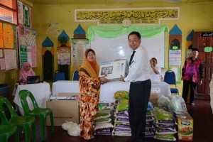 Mr. Arifin presenting the computer and groceries to Ustazah Zubaidah.